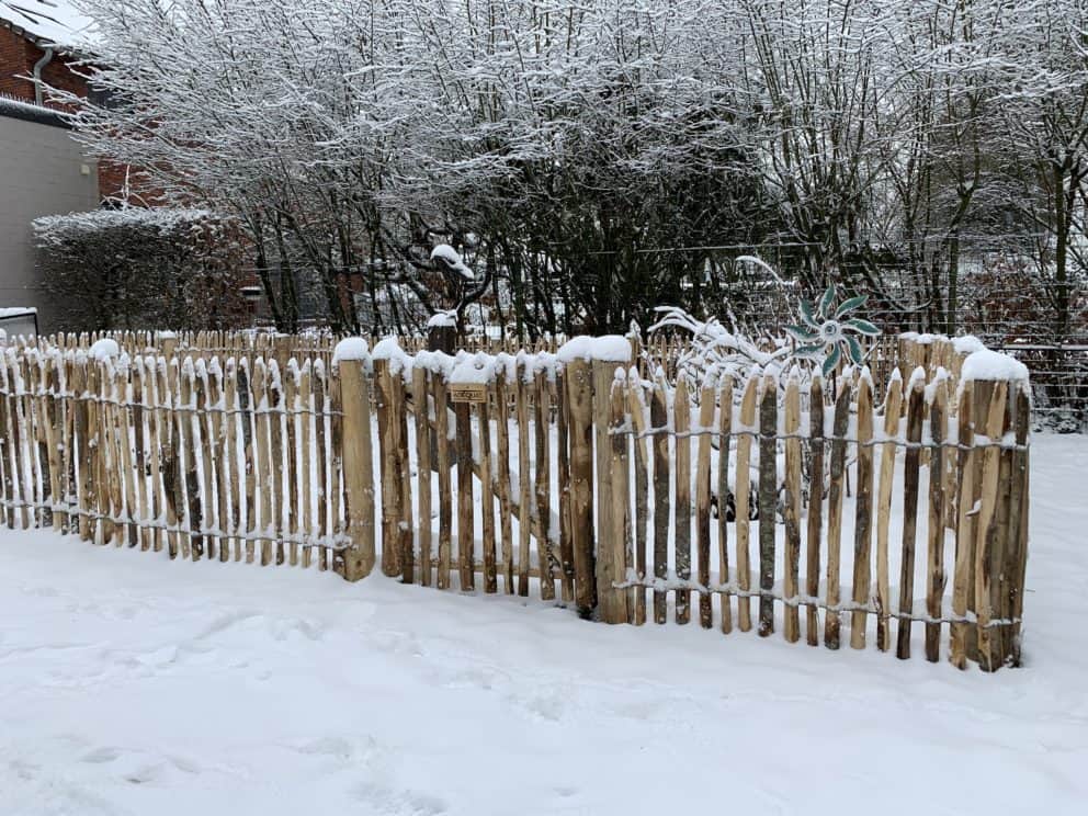 Frans schapenhek van 80 cm hoog met een latafstand van 4 cm en een franse rondhoutpoort van 80 cm bij 80 cm in een tuin met heel veel sneeuw.