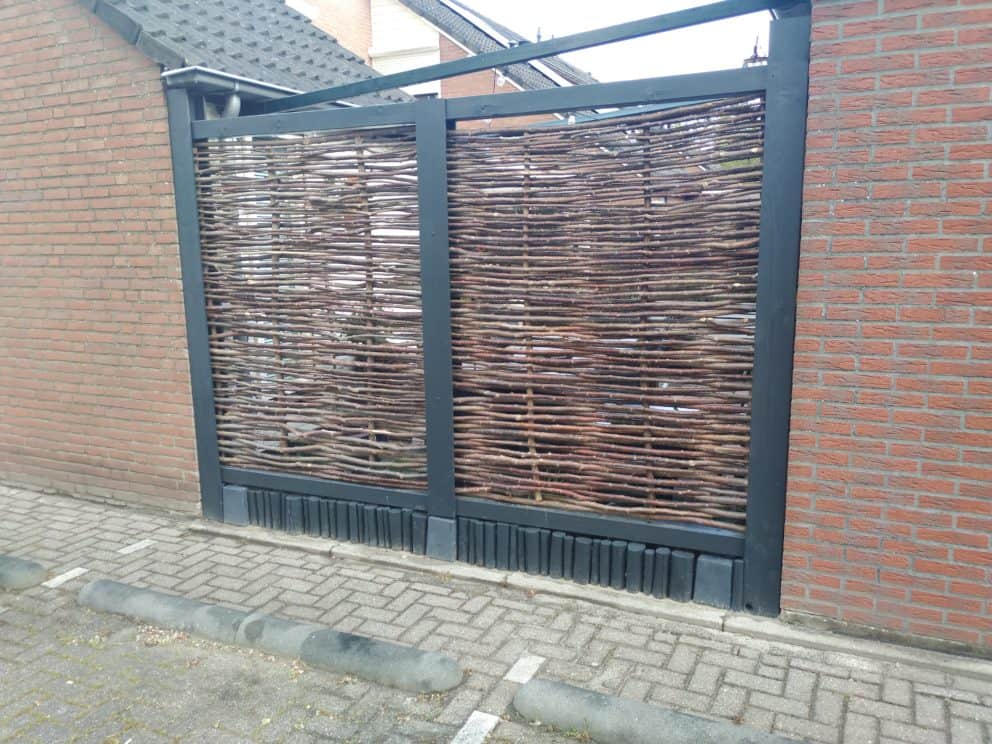 Somme 1 hazelaarschermen als creatieve afrastering in een tuin tussen twee stenen muren.