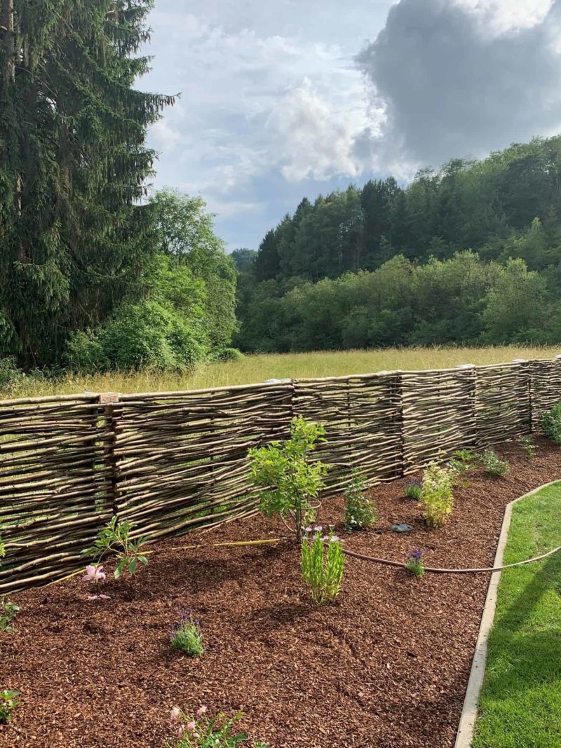 Hazelaarscherm Somme 3 als lage afrastering gebruikt in een tuin met een uitzicht over de bossen.