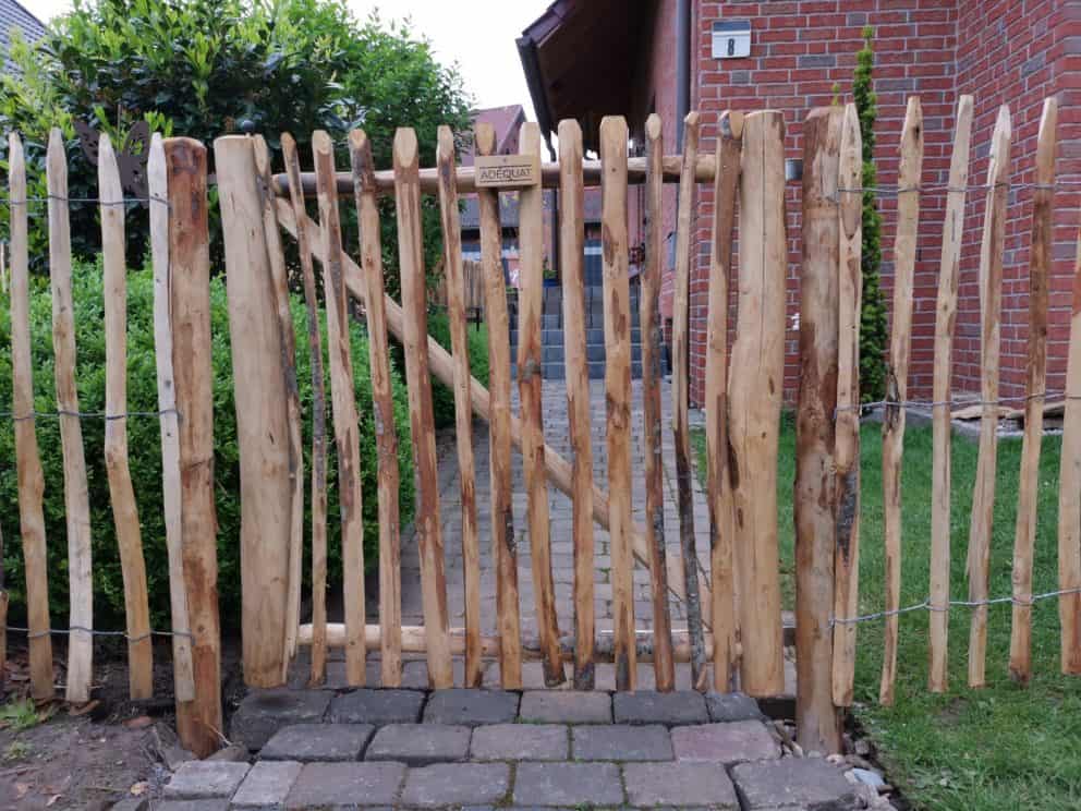 Franse rondhoutpoort vn 120 cm breed bij 120 cm hoog tussen schapenhek van dezelfde hoogte geplaatst om als afscheiding in de tuin te fungeren.