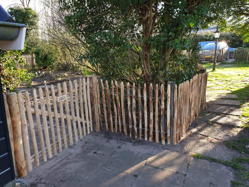 Franse rondhoutpoort van 120 cm breed geplaatst aan schapenhek om als afrastering en doorgang te fungeren.