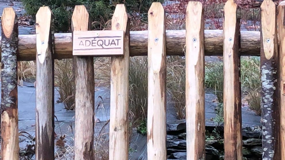 Franse rondhoutpoort van 150 cm hoog met een houten bordje met Adéquat erop gebrand.