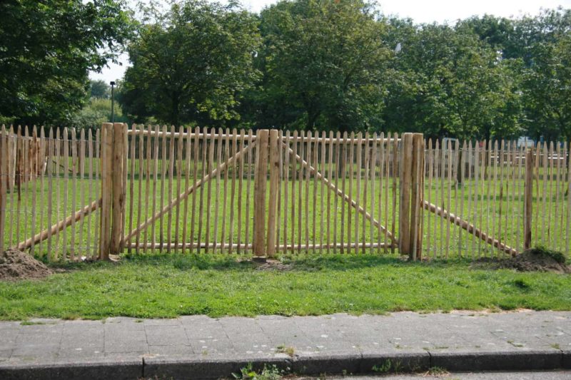 Dubbele Franse rondhoutpoort van kastanjehout van 150 cm hoog en 180 cm breed per poortdeel bevestigd tussen een schapenhek omheining van 150 cm hoog.