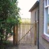 Franse rondhoutpoort van 120 cm hoogals doorgang tussen een woning en een heg