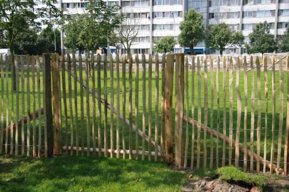 Franse rondhoutpoort van 150 cm hoog en 180 cm breed als doorgang tussen een omheining van schapenhek