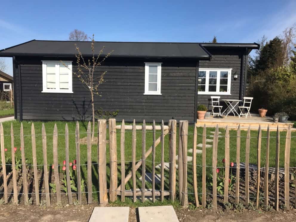 Schapenhek van 100 cm met een latafstand van 8 cm en een Franse rondhoutpoort geplaatst in een tuin in Denemarken.