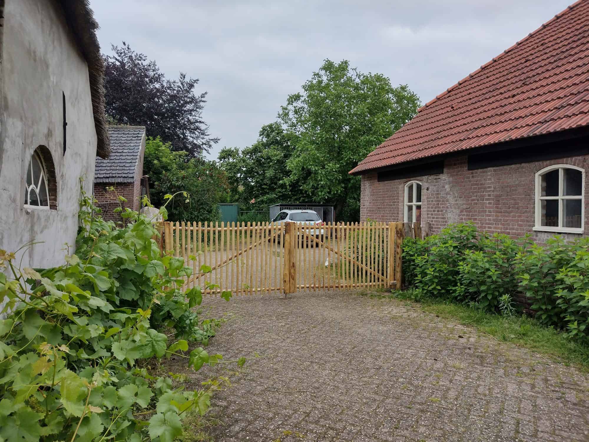 Dubbele Franse rondhoutpoort van 299 cm breed bij 120 cm hoog per poortdeel als doorgang tussen twee gebouwen