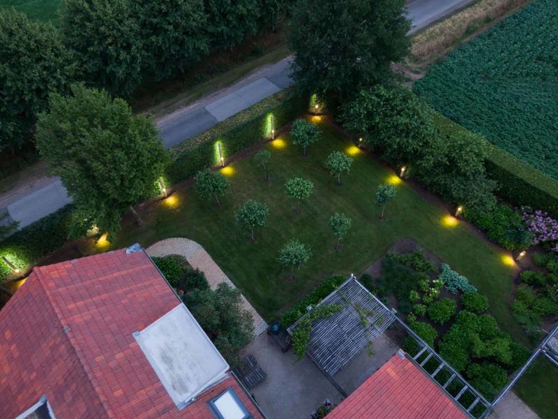 Bovenaanzicht van een tuin waar de ronde Billy tuinverlichting in een rij staat voor de heg.