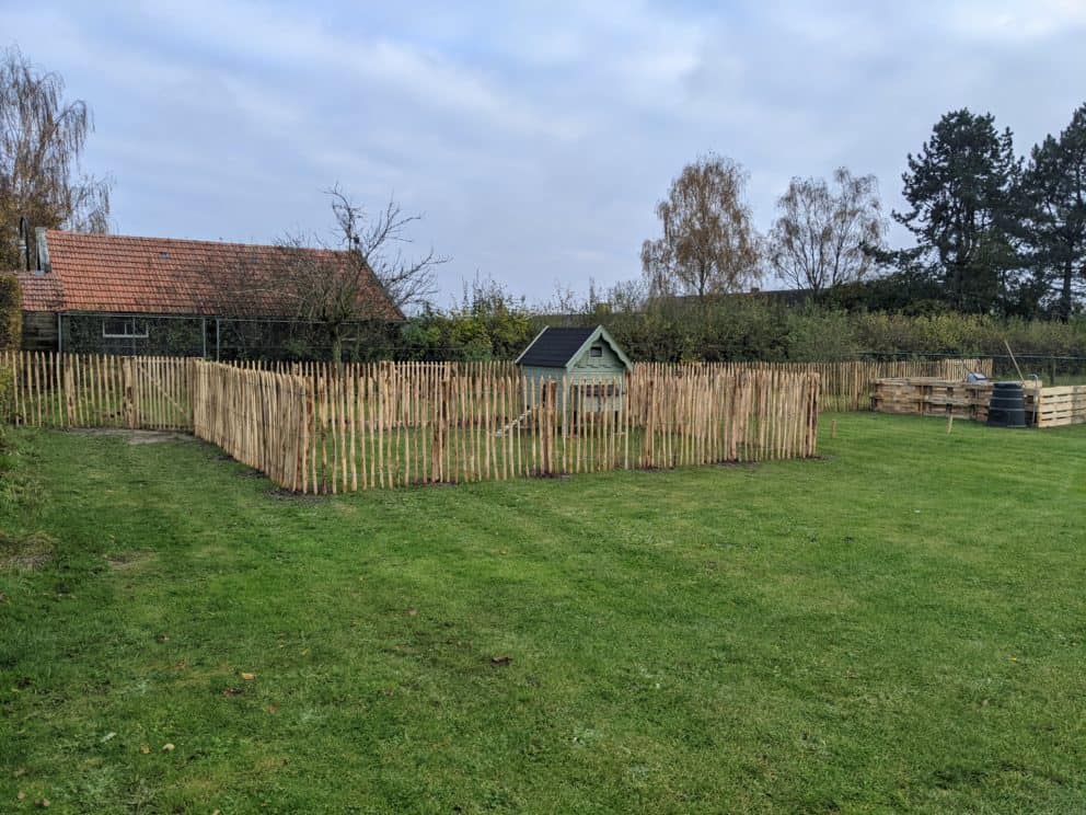 Franse rondhoutpoort van 120 cm breed bij 120 cm hoog als doorgang bij een kippenren omheind met schapenhek an 120 cm hoog met een latafstand van 6 cm