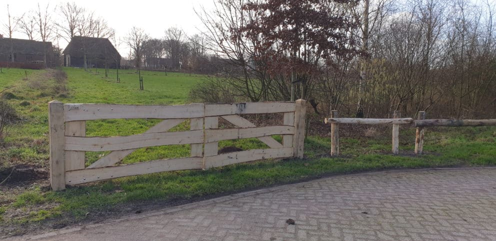 Dubbele kastenje boerenlandhek van 205 cm breed en 110 cm hoog met kastanje schaaldelen. Deze poort staat aan het begin van de wei als toegangspoort.