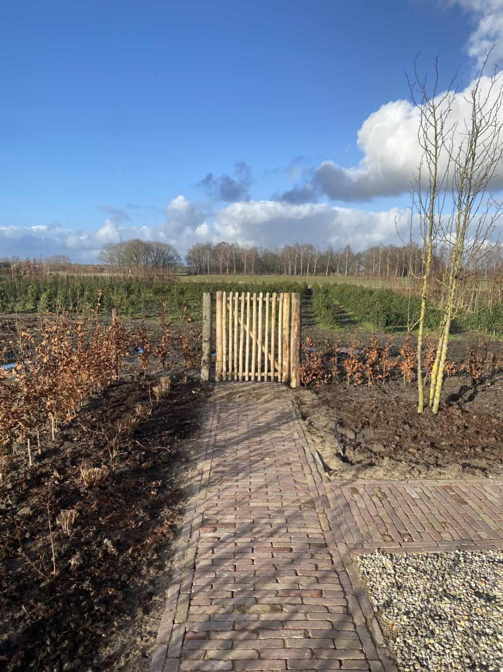 Franse rondhoutpoort van 100 cm breed bij 100 cm hoog als toegang naar de wei met bomen.