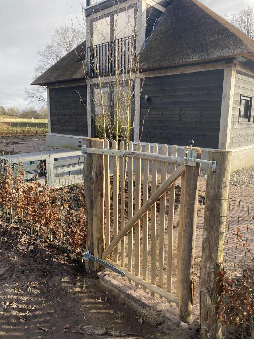 Franse rondhoutpoort van 100 cm hoog en 100 cm breed als toegang naar de tuin van de woning.