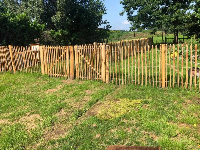 Twee keer een enkele Franse rondhoutpoort van 120 cm hoog bij 120 cm breed naast elkaar geplaatst tussen schapenhek als omheining bij een moestuin