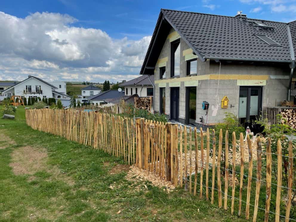 Franse rondhoutpoort van 100 cm hoog bij 80 cm breed als doorgang naar een woning met schapenhek als omheining ernaast.