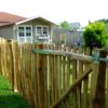 Franse rondhoutpoort van 120 cm breed bij 120 cm hoog bevestigd aan schapenhek van 120 cm hoog met een latafstand van 4 cm als afscheiding in een tuin.