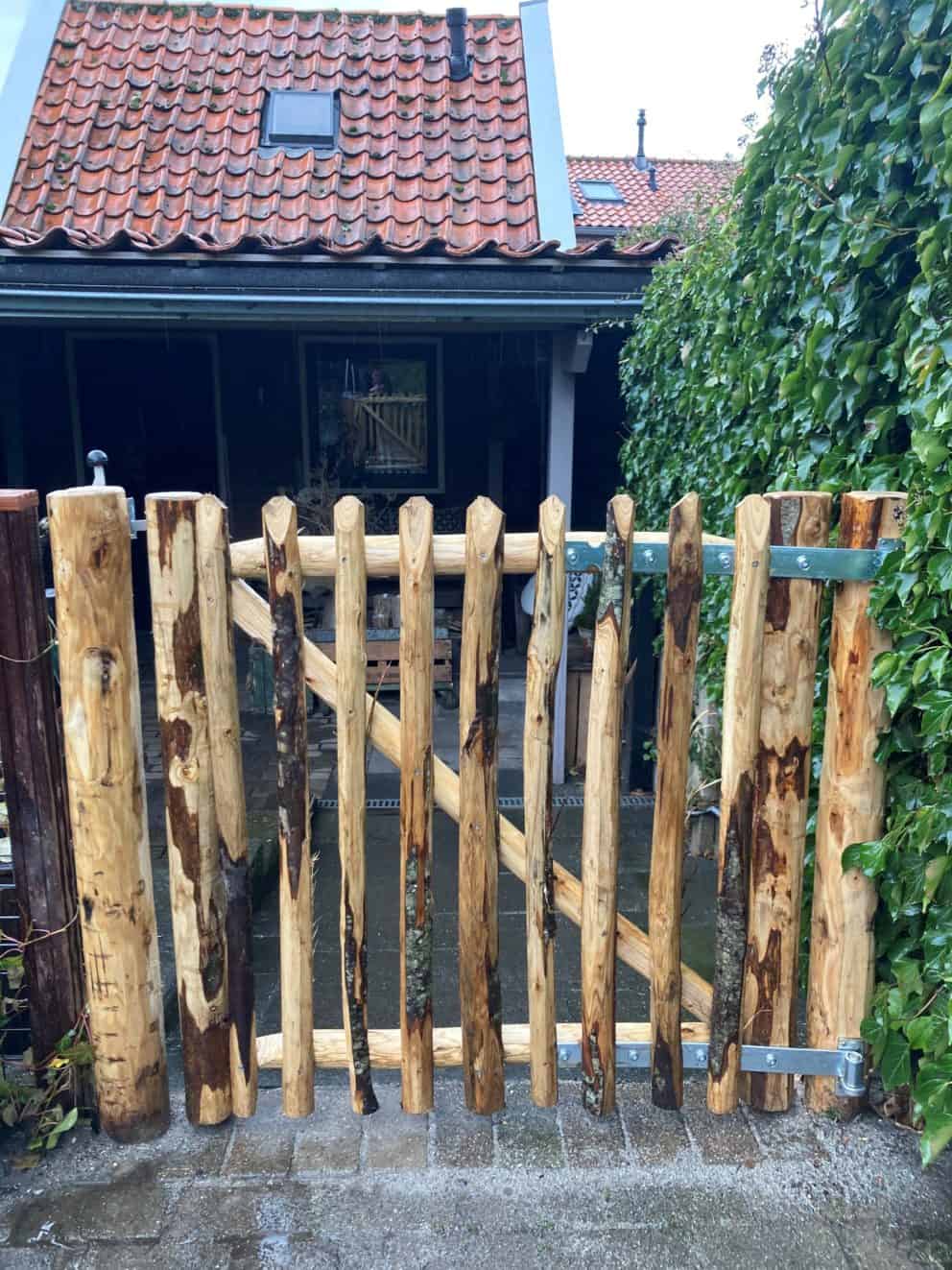 Kastanje rondhoutpoort van 100 cm hoog en 100 cm breed als doorgang van en naar de achterkant van een huis.