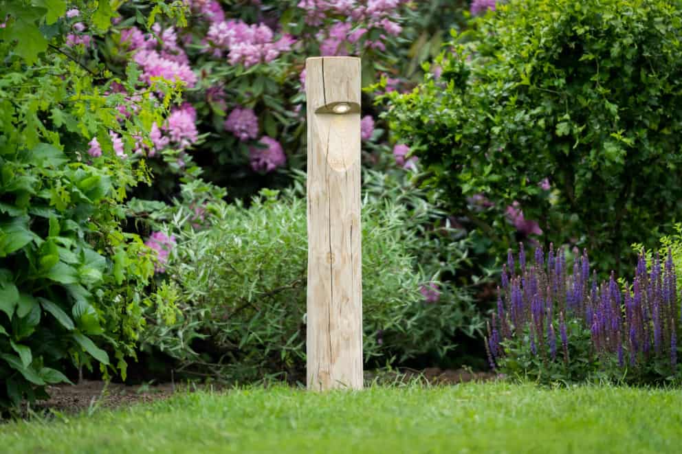 Rond houten tuinverlichting Billy in tuin met veel bloemen