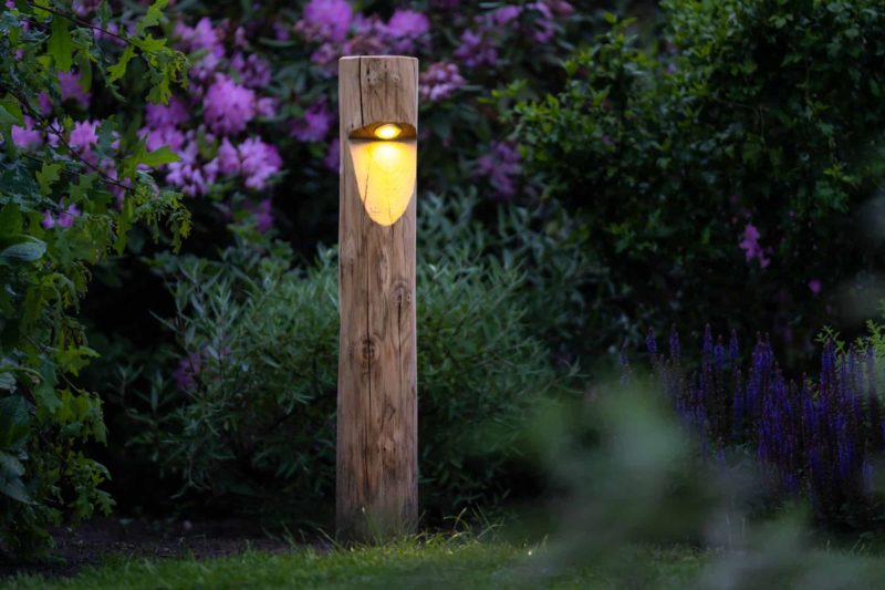 Rond houten tuinverlichting Billy in tuin met veel bloemen