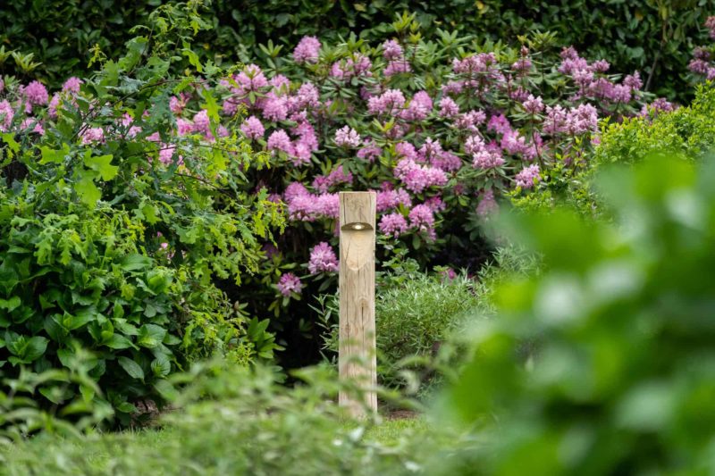 Rond houten tuinverlichting Billy in tuin met veel bloemen