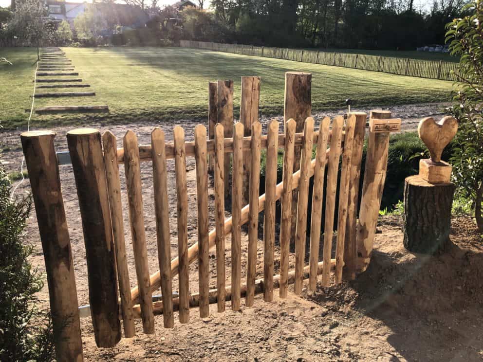 Franse rondhoutpoort van 80 cm hoog en 150 cm breed als toegang naar een tuin.