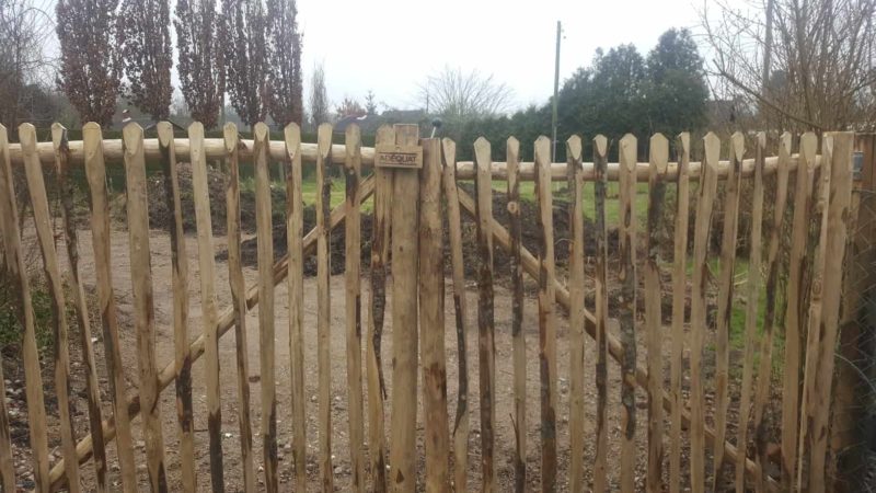 Dubbele franse rondhoutpoort van 200 cm hoog en 100 cm breed per poortdeel gebruikt als doorgang van en naar een tuin.