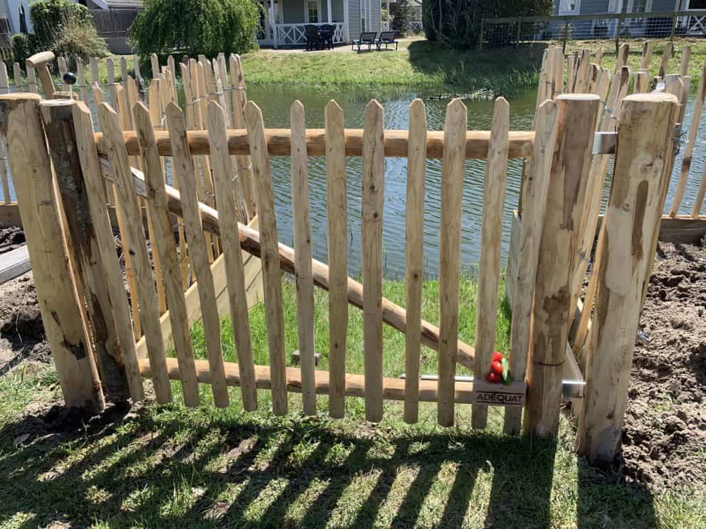 Franse rondhoutpoort met een hoogte van 120 cm en een breedte van 80 cm gebruikt als toegang van de tuin naar het water.