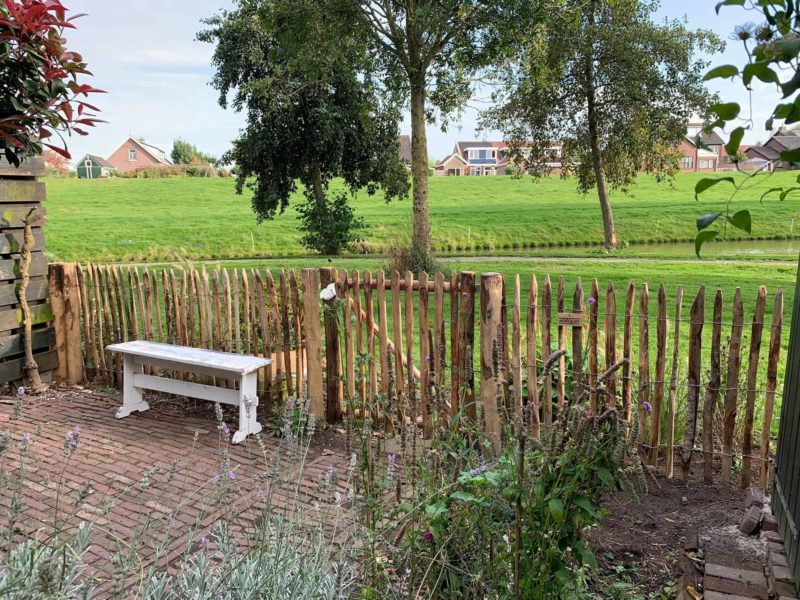 Franse kastanje rondhoutpoort van 100 cm hoog bij 100 cm breed bevestigd aan schapenhek als toegang en omheining bij een woning.