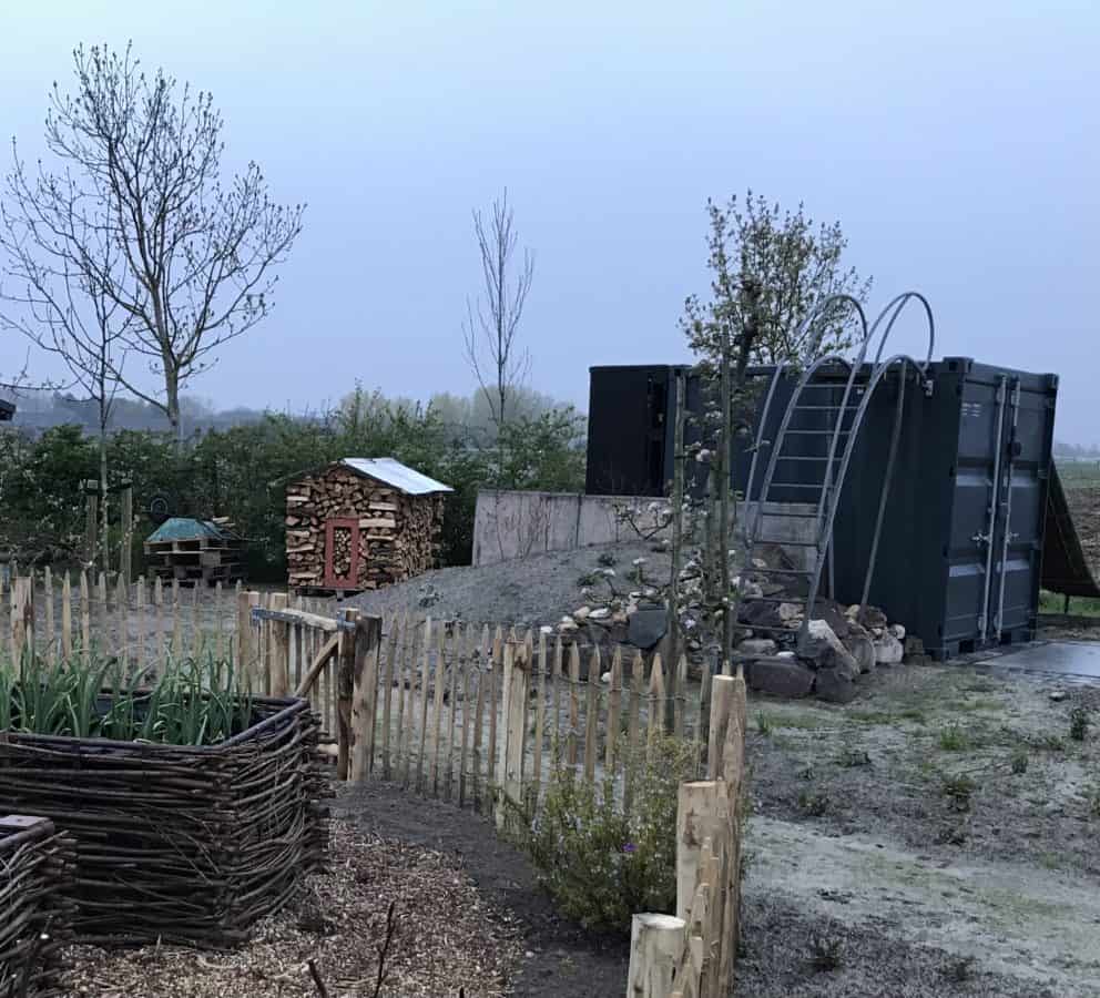 Frans schapenhek kastanje 80 cm hoog met latafstand 6 cm en een raamwerkpoort van 80 cm breed bij 80 cm hoog als afscheiding en doorgang in een tuin.