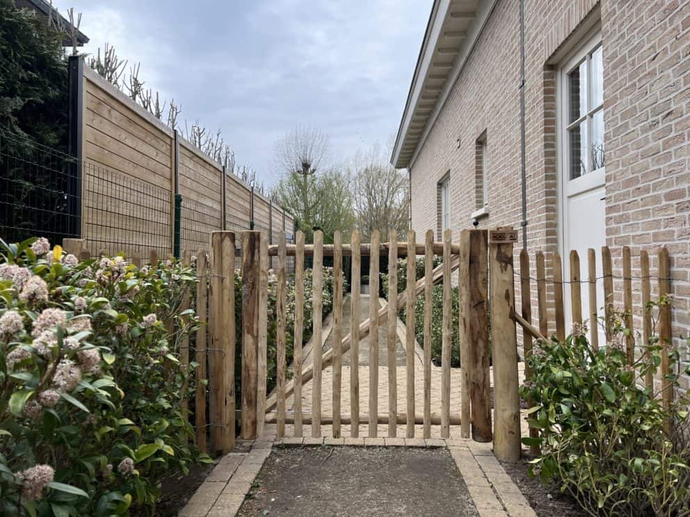 Robinia schapenhek 100 cm hoog, latafstand 4 cm met Franse rondhoutpoort 120 breed bij 100 cm hoog als toegangspoort tussen de woning en de omheining van de tuin.