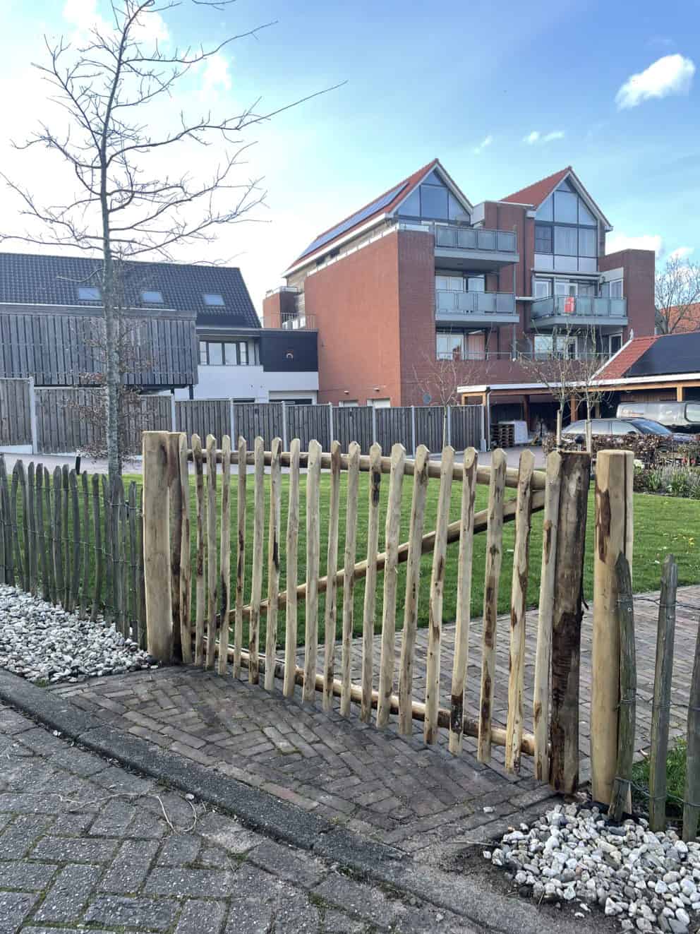 Linksdraaiende Franse rondhoutpoort van 180 cm breed en 100 cm hoog als toegangspoort in de voortuin van een huis.