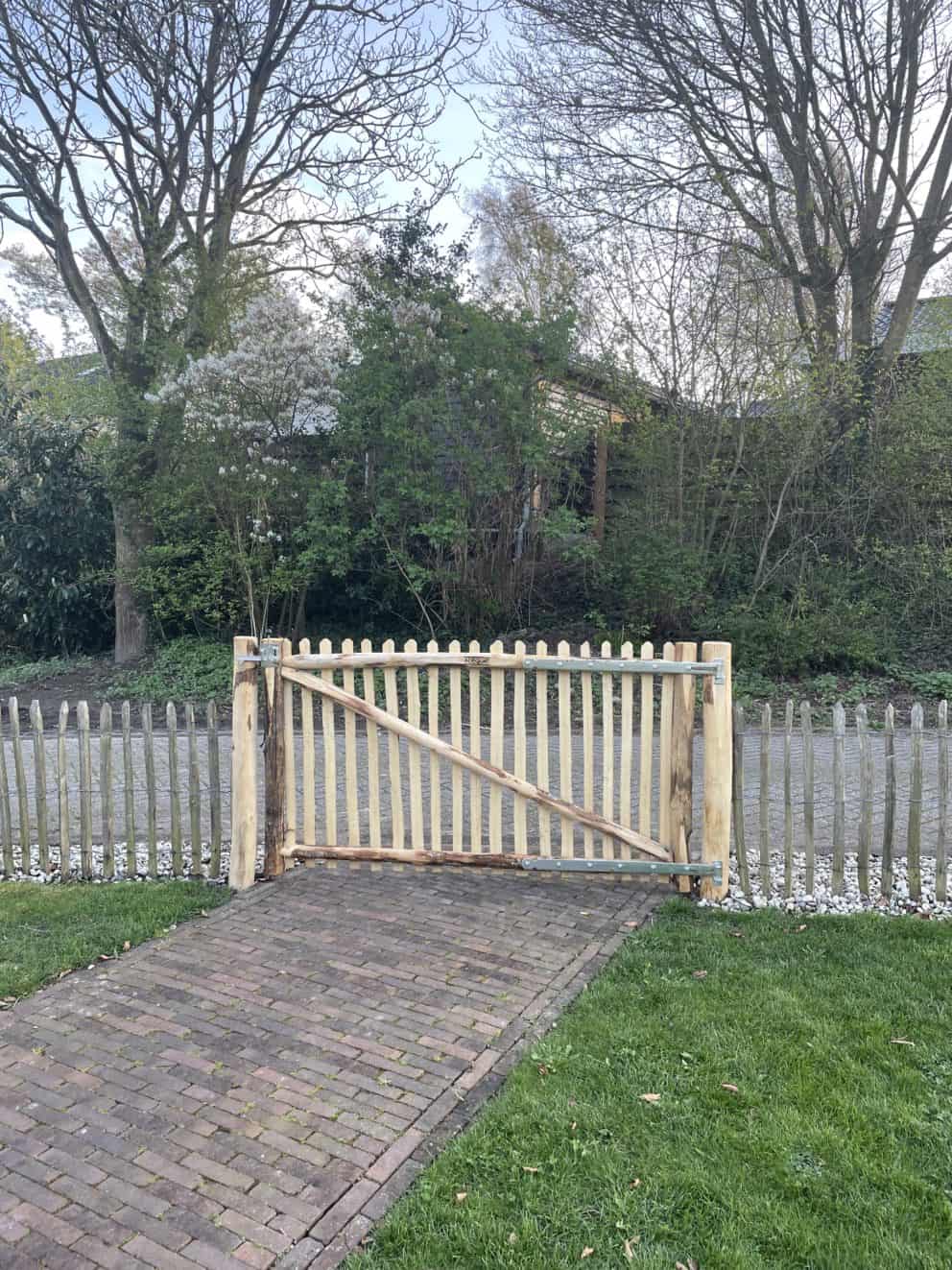 Linksdraaiende Franse rondhoutpoort van 180 cm breed en 100 cm hoog als toegangspoort in de voortuin van een huis.