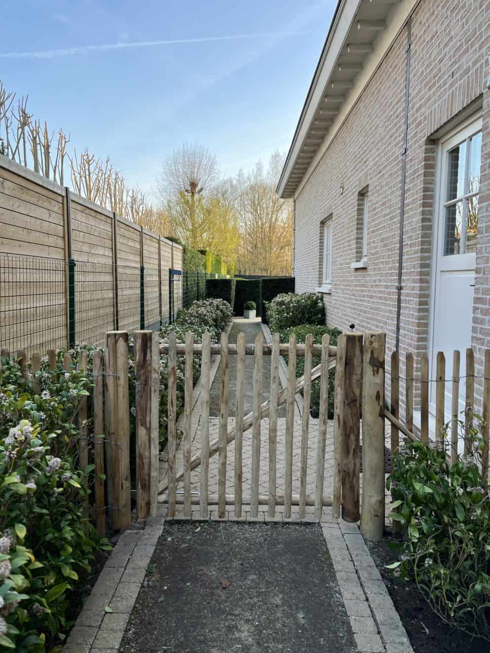 Robinia schapenhek 100 cm hoog, latafstand 4 cm met Franse rondhoutpoort 120 breed bij 100 cm hoog als toegangspoort tussen de woning en de omheining van de tuin.