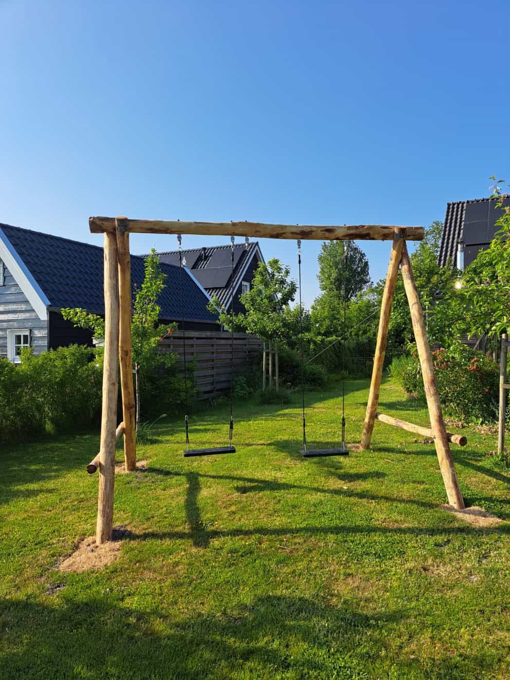 Houten schommel van kastanjehouten palen met twee schommels in een tuin