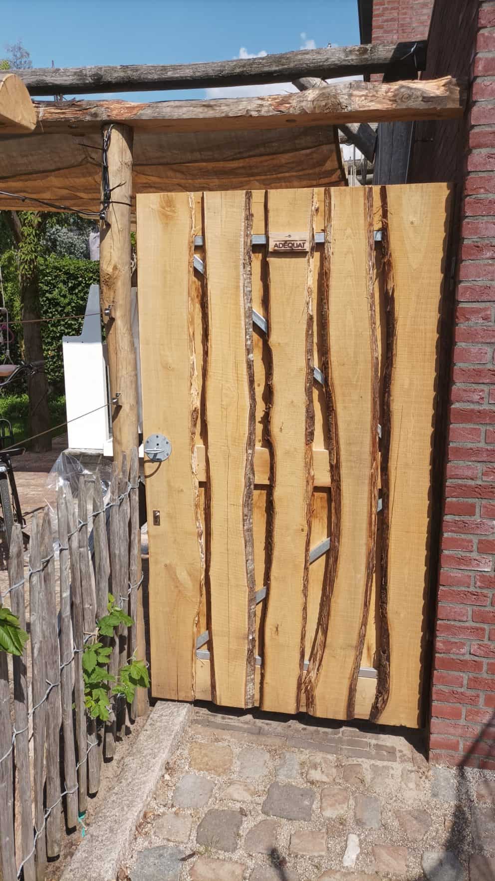 Poort gemaakt van kastanjehouten schaaldelen in de maat 2x15 - 22x250 cm De poort is bevestigd aan de zijkant van het huis en wordt gebruikt als toegangspoort naar de tuin.