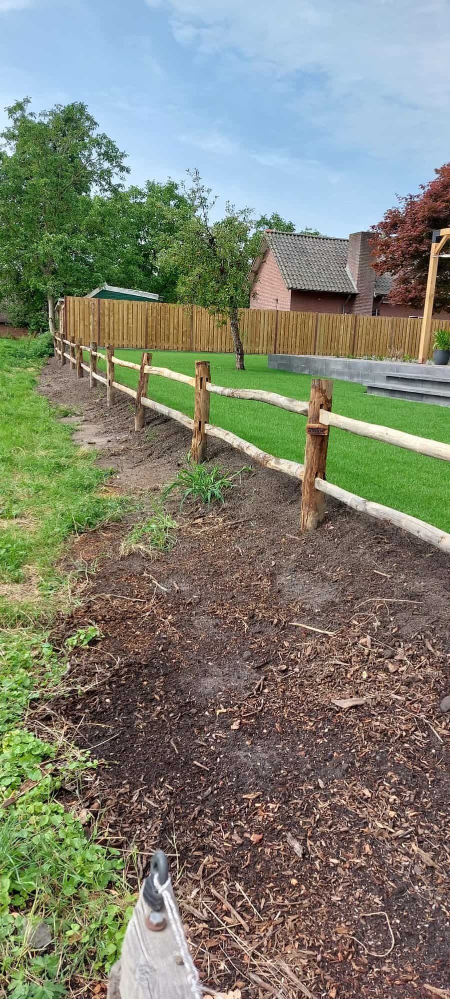 Post & rail niveau 2 rond met liggers als omheining in de tuin bij een huis.