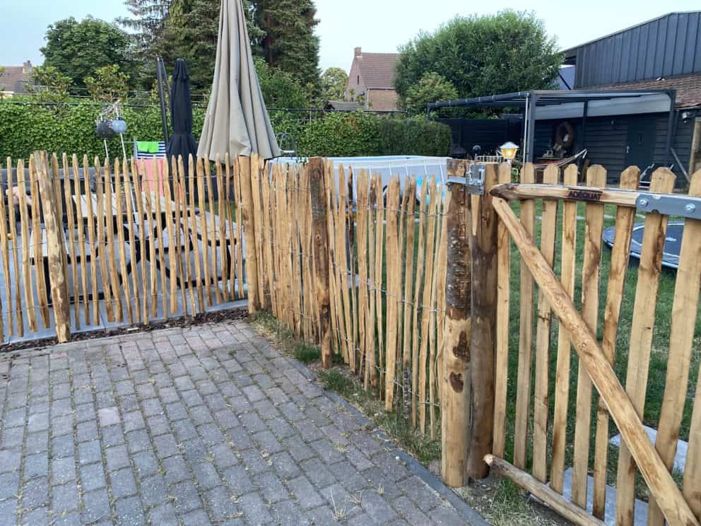 Frans schapenhek 120 cm hoog en latafstand 2 cm en een linksdraaiende rondhoutpoort van 100 breed bij 120 hoog als afscheiding in een tuin tussen privé en b&b