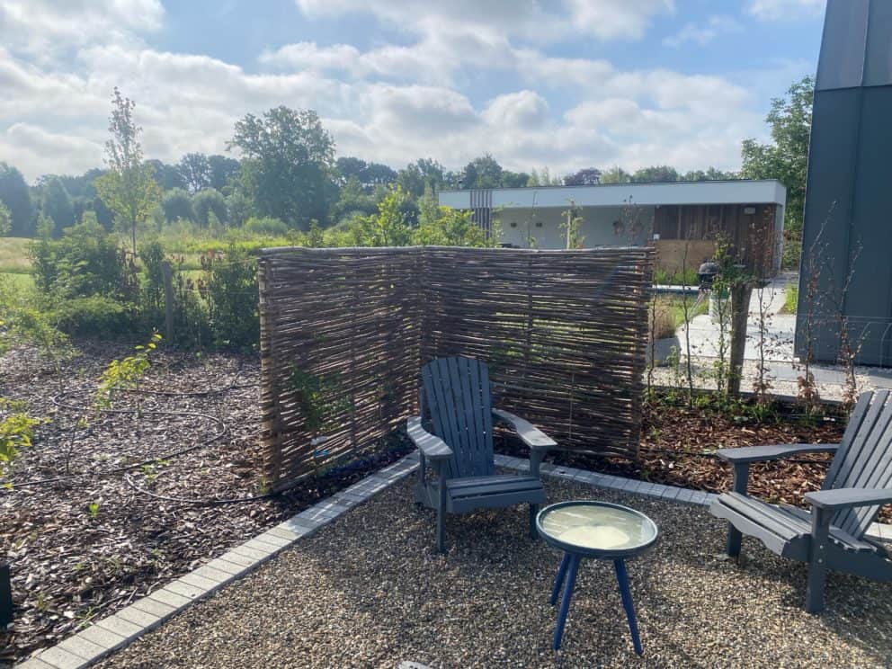 Hazelaarscherm Somme 1 van 150 cm breed bij 180 cm hoog geplaatst in een tuin als afrastering bij een lounge hoekje.