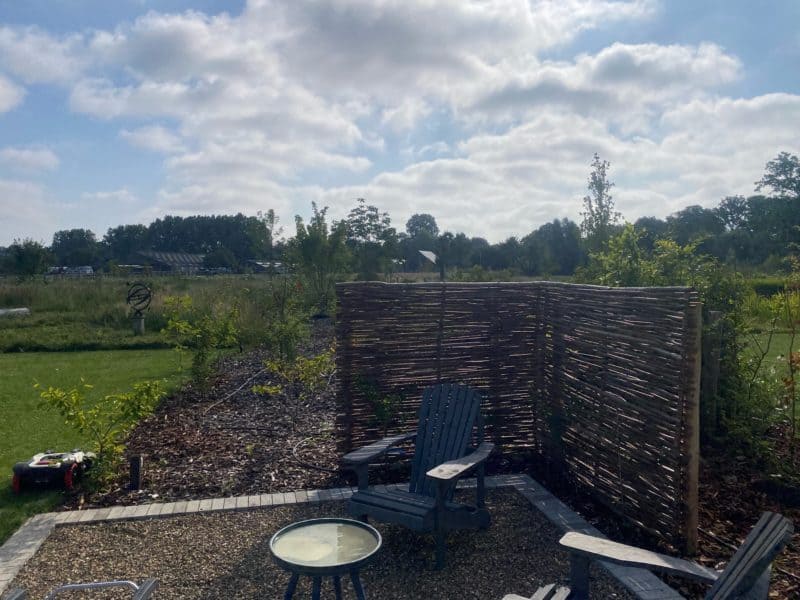 Hazelaarscherm Somme 1 van 150 cm breed bij 180 cm hoog geplaatst in een tuin als afrastering bij een lounge hoekje.