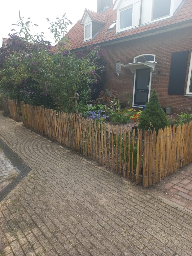 Frans schapenhek van kastanje van 80 cm hoog met een latafstand van 4 cm met kastanje palen van 125 cm lang en een diameter van 7-9 cm gebruikt als omheining in de voortuin