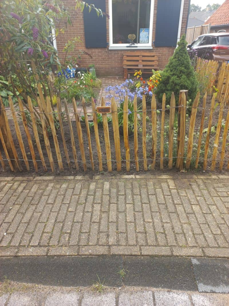 Frans schapenhek van kastanje van 80 cm hoog met een latafstand van 4 cm met kastanje palen van 125 cm lang en een diameter van 7-9 cm gebruikt als omheining in de voortuin