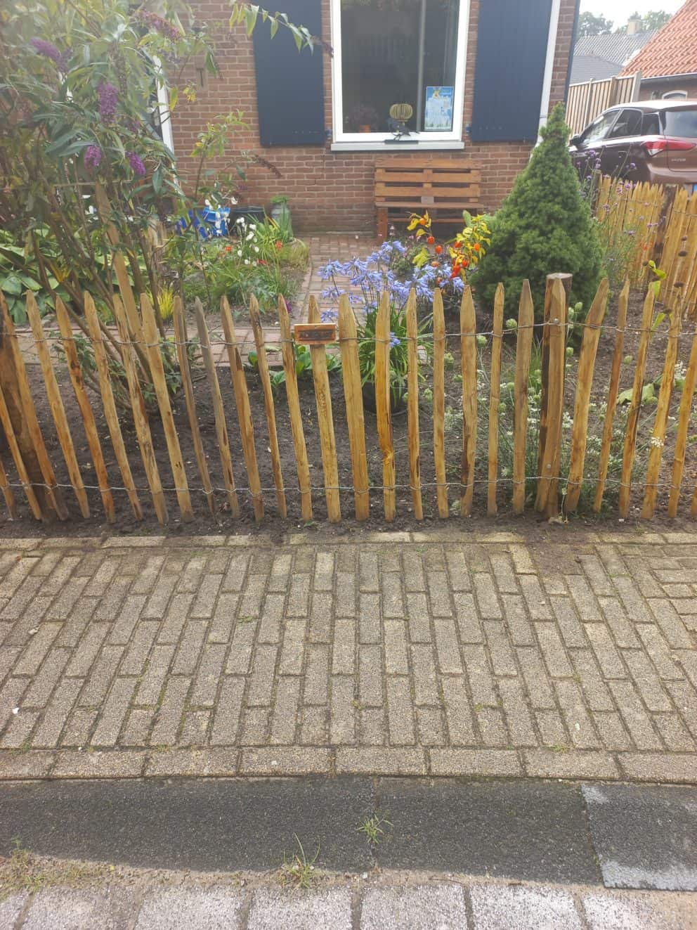 Frans schapenhek van kastanje van 80 cm hoog met een latafstand van 4 cm met kastanje palen van 125 cm lang en een diameter van 7-9 cm gebruikt als omheining in de voortuin