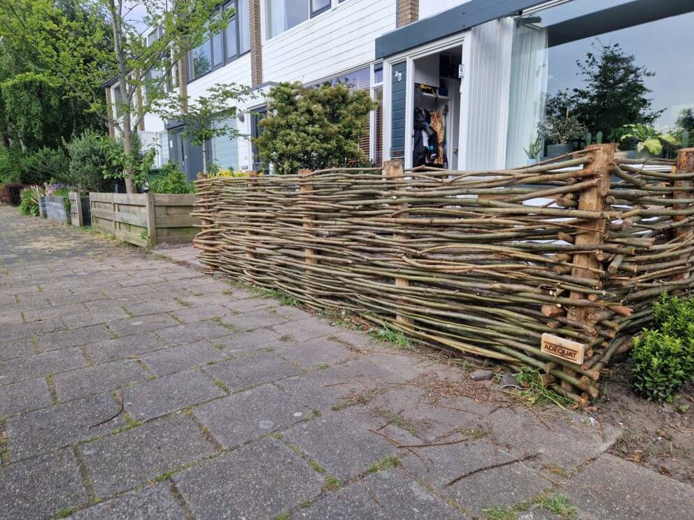 Kastanje paal 120 cm lang met een diameter van 7-9 cm met daartussen gevlochten wilgentenen in de voortuin