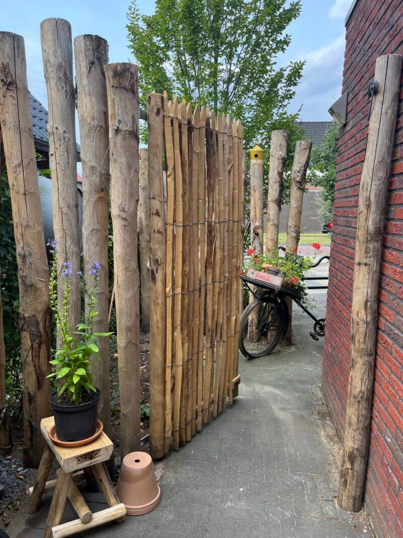 Poort gemaakt van Frans schapenhek 200 cm hoog, latafstand 4 cm met Franse raamwerkpoort 100 cm breed bij 200 cm hoog met een kastanje krukje