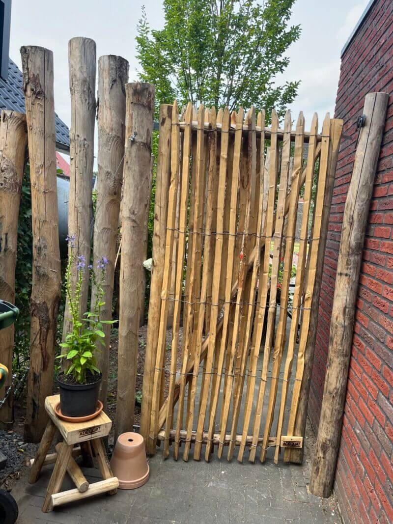 Poort gemaakt van Frans schapenhek 200 cm hoog, latafstand 4 cm met Franse raamwerkpoort 100 cm breed bij 200 cm hoog met een kastanje krukje