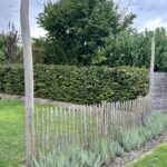 Omheining bij speeltuin gemaakt van Frans schapenhek 100 cm hoog, latafstand 4 cm met robinia palen 160 en 400 cm lang, diameter 10/12 cm met een lichtsnoer eraan.