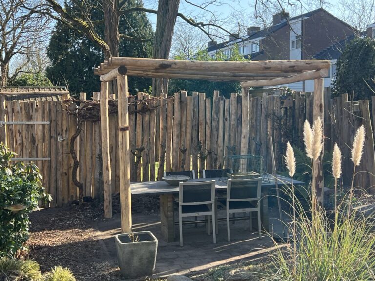 Pergola en omheining gemaakt van kastanje paal 250 en 300 cm lang, diameter 10/12 cm met kastanje paal 300 cm lang, diameter 10/12 cm met pen (op maat gemaakt) en halfronde kastanje paal 200 cm lang, diameter 10/12 cm. Poort gemaakt van palen met heng 80 cm, duim en poorsluiting simpel