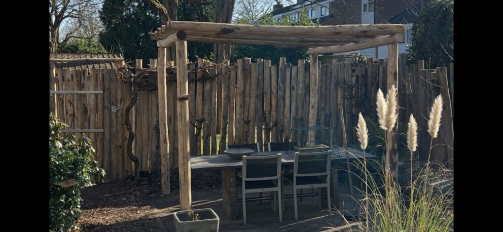 Pergola en omheining gemaakt van kastanje paal 250 en 300 cm lang, diameter 10/12 cm met kastanje paal 300 cm lang, diameter 10/12 cm met pen (op maat gemaakt) en halfronde kastanje paal 200 cm lang, diameter 10/12 cm. Poort gemaakt van palen met heng 80 cm, duim en poorsluiting simpel