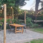 Kastanje paal 300 cm lang, diameter 13/16 cm bij een terras gebruikt om een lichtsnoer aan te bevestigen