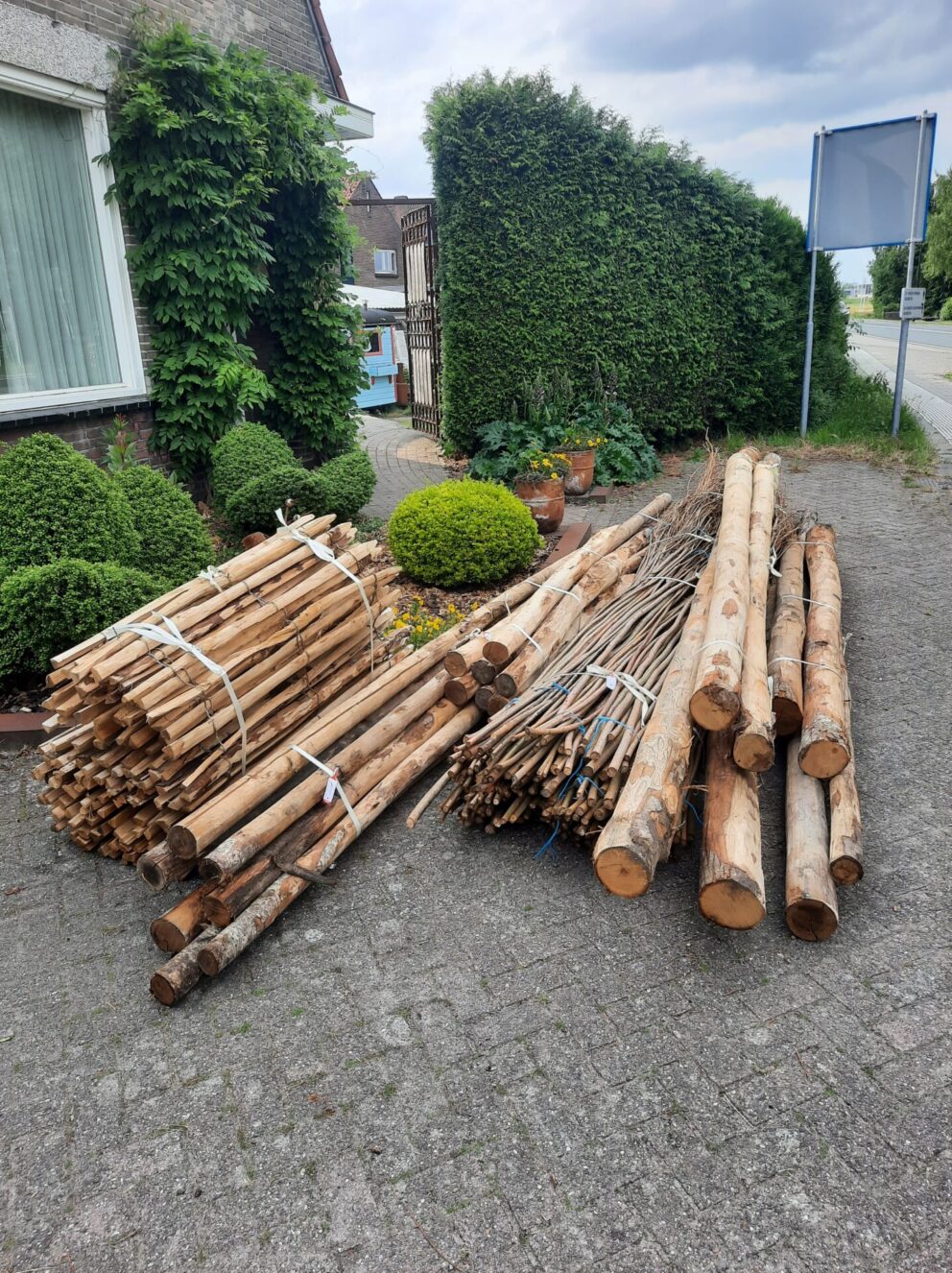Kastanjepaal 300 cm, diameter 4/6 cm, ongepunt, kastanje paal 200 cm lang, diameter 7/9 cm, gepunt, robinia paal 200 cm lang, diameter 8/10 cm, geschild gepunt, kastanje paal 175 cm lang, diameter 10/12 cm, gepunt, kastanje paal 200 cm lang, diameter 7/9 cm, halfrond, kastanje paal 250 cm lang, diameter 7/9 cm, halfrond en kastanje paal 250 cm lang, diameter 7/9 cm, gepunt. Overkapping met wilgentenen. Producten wanneer ze net zijn geleverd.